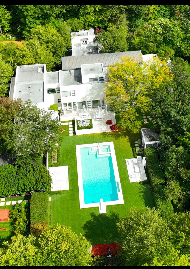 Aerial view of luxury estate with artificial turf and pool by Greenlight Design Group